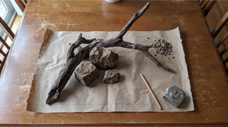 Driftwood and aquarium rocks being arranged on a table before placement in a freshwater aquascape